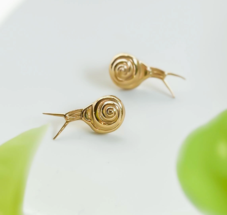 Gold snail-shaped earrings on a light background