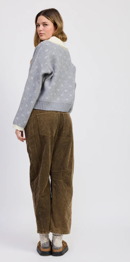 Person wearing a gray sweater and brown corduroy pants on a white background