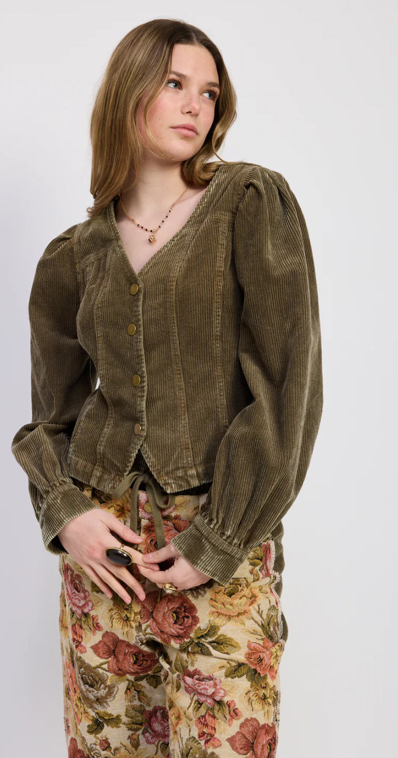 Woman wearing a vintage-style green jacket and floral skirt on a white background