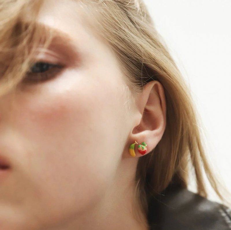 Close-up of a person wearing colorful earrings with a blurred background