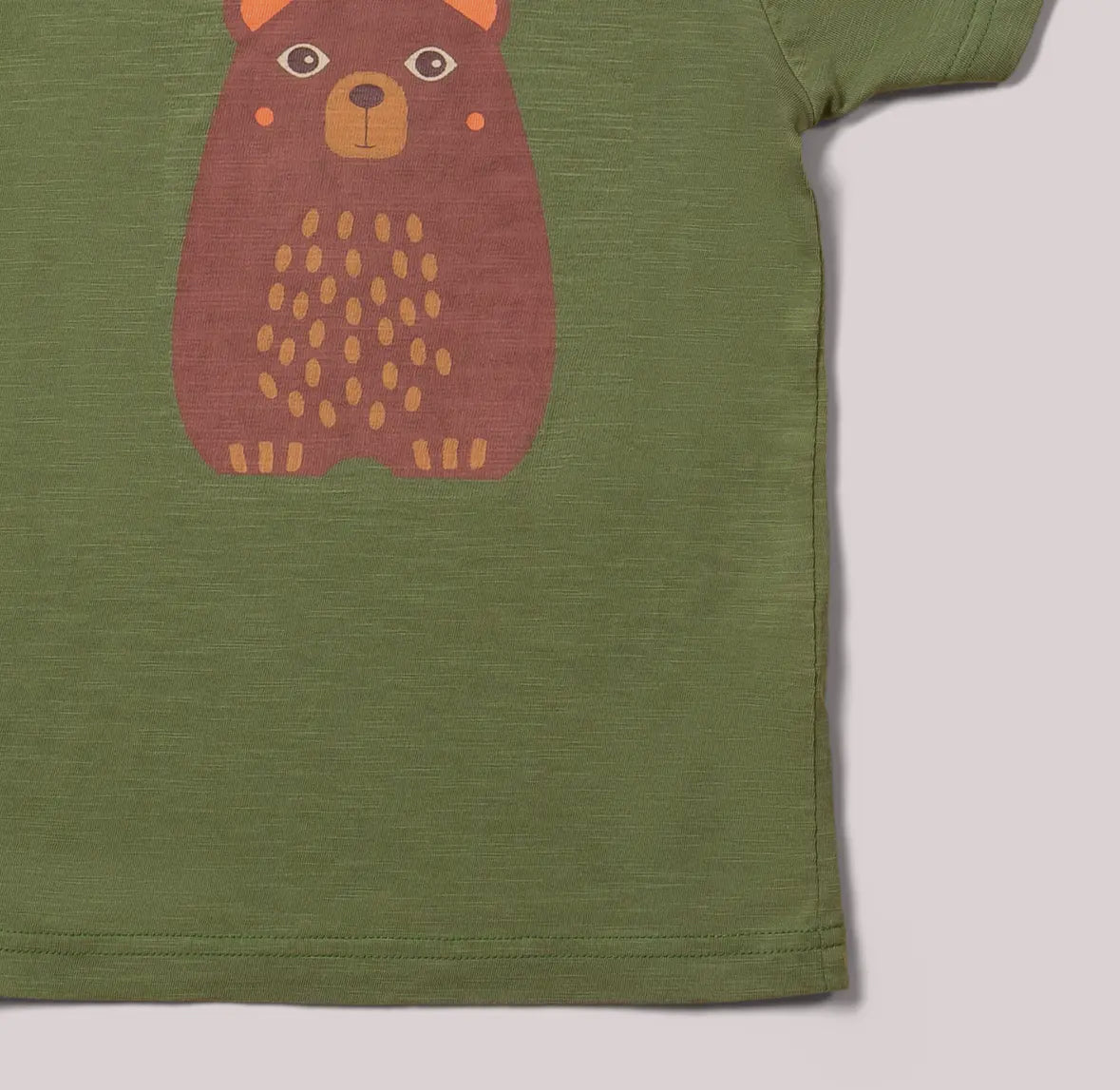 Green t-shirt with a bear graphic on a light gray background