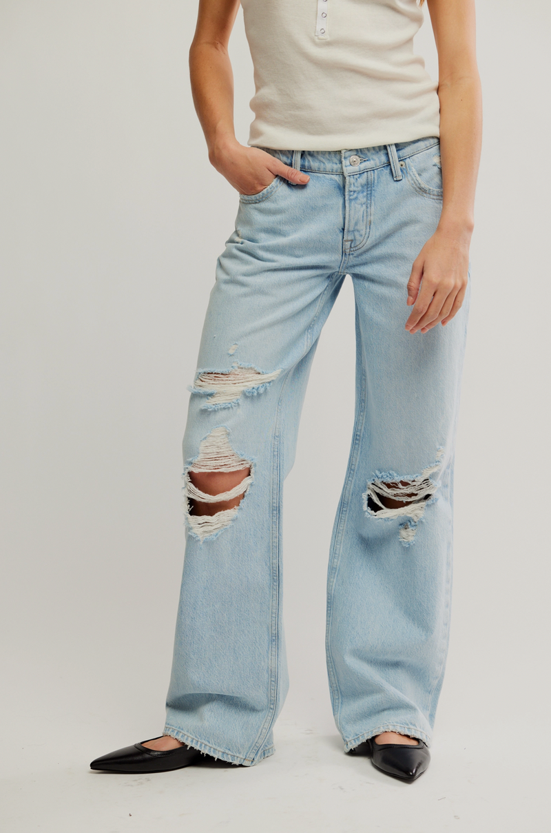 Person wearing light blue distressed jeans on a white background