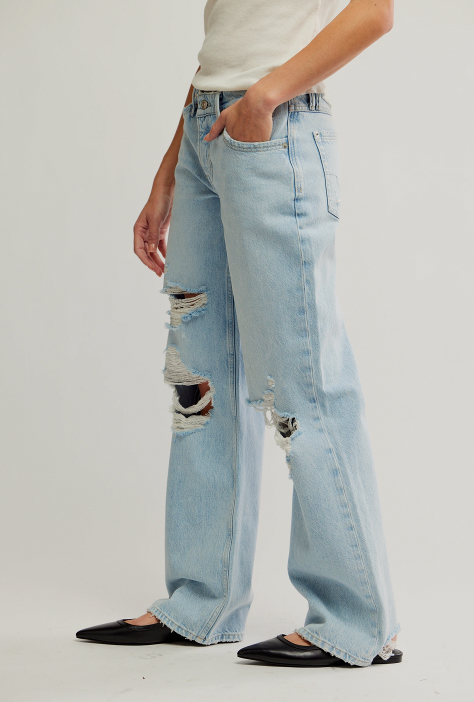 Light blue distressed jeans worn by a person on a white background