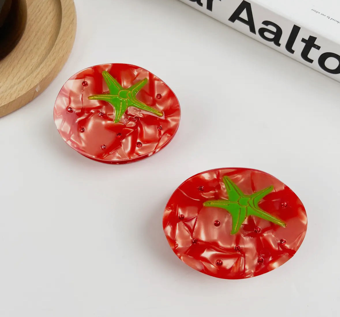 Red tomato-shaped buttons with green stems on a white surface.