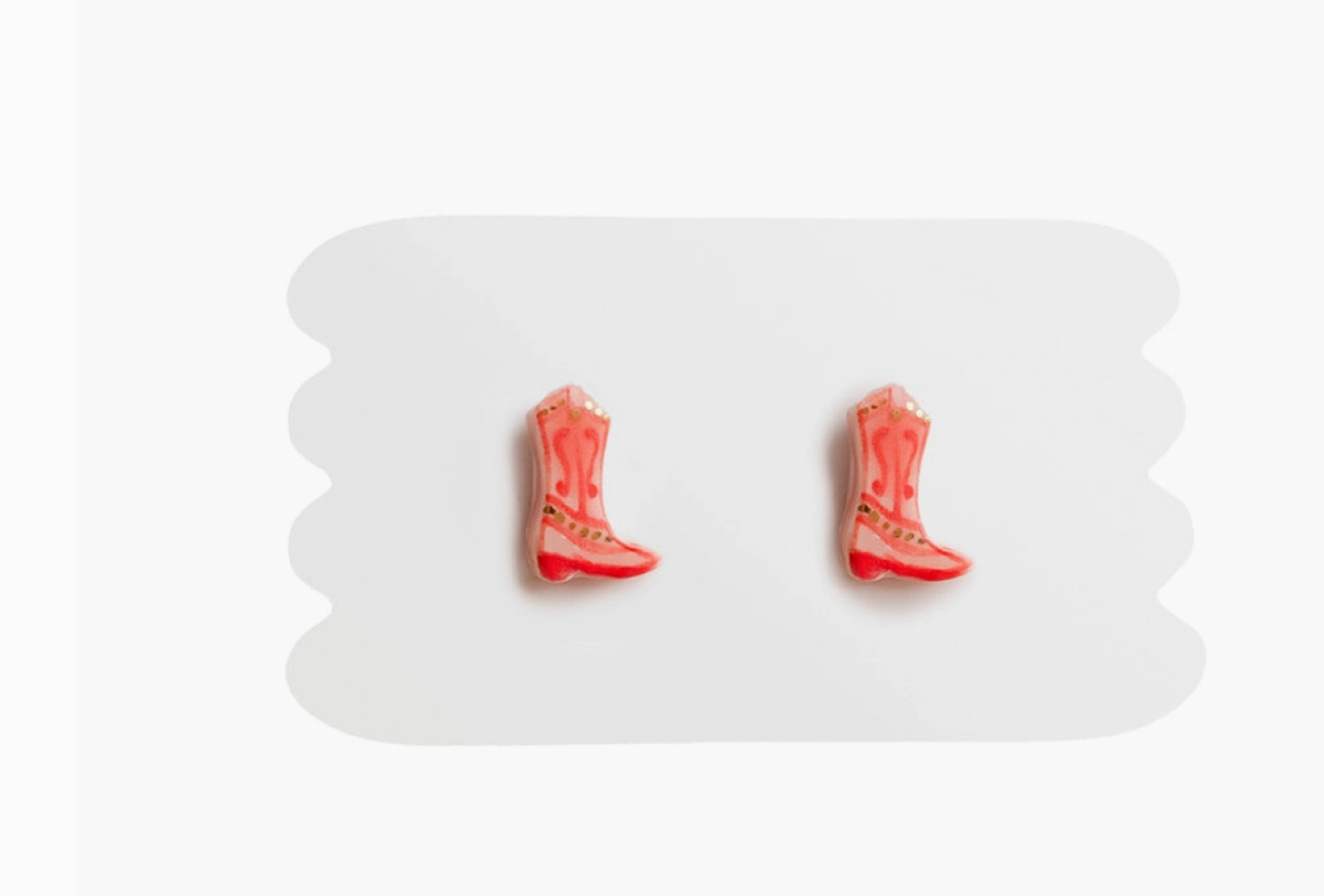 Pink cowboy boot earrings on a white cardboard