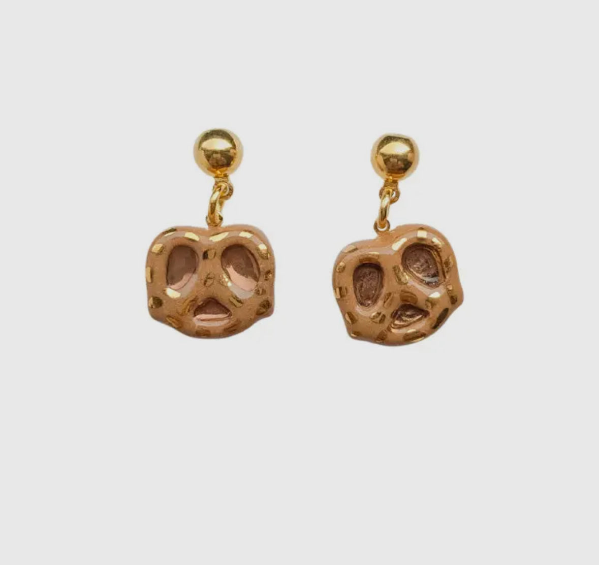 Gold pretzel-shaped earrings on a white background