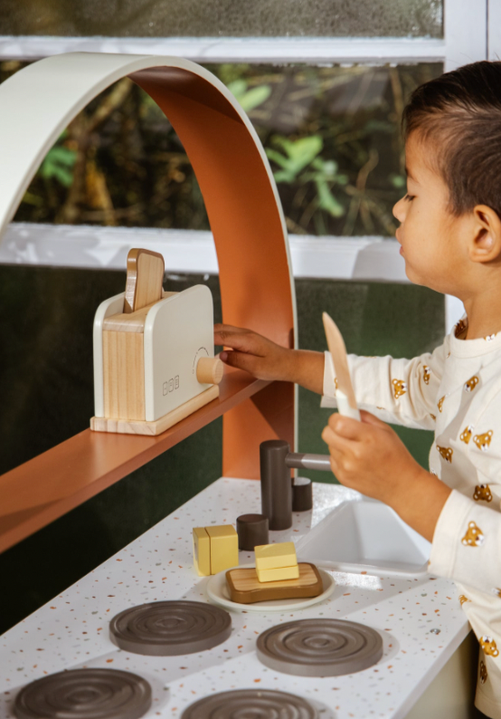 Child playing with wooden toys on a play kitchen set