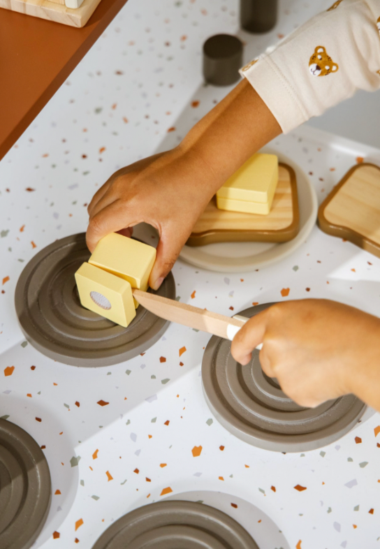 Person preparing to fill a muffin tin with butter using a wooden spatula.