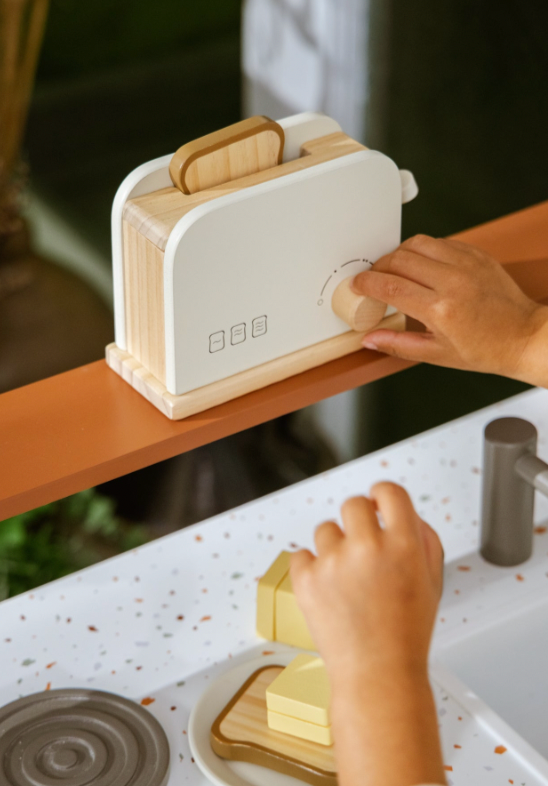 Children's toy toaster with wooden handle on a kitchen counter.