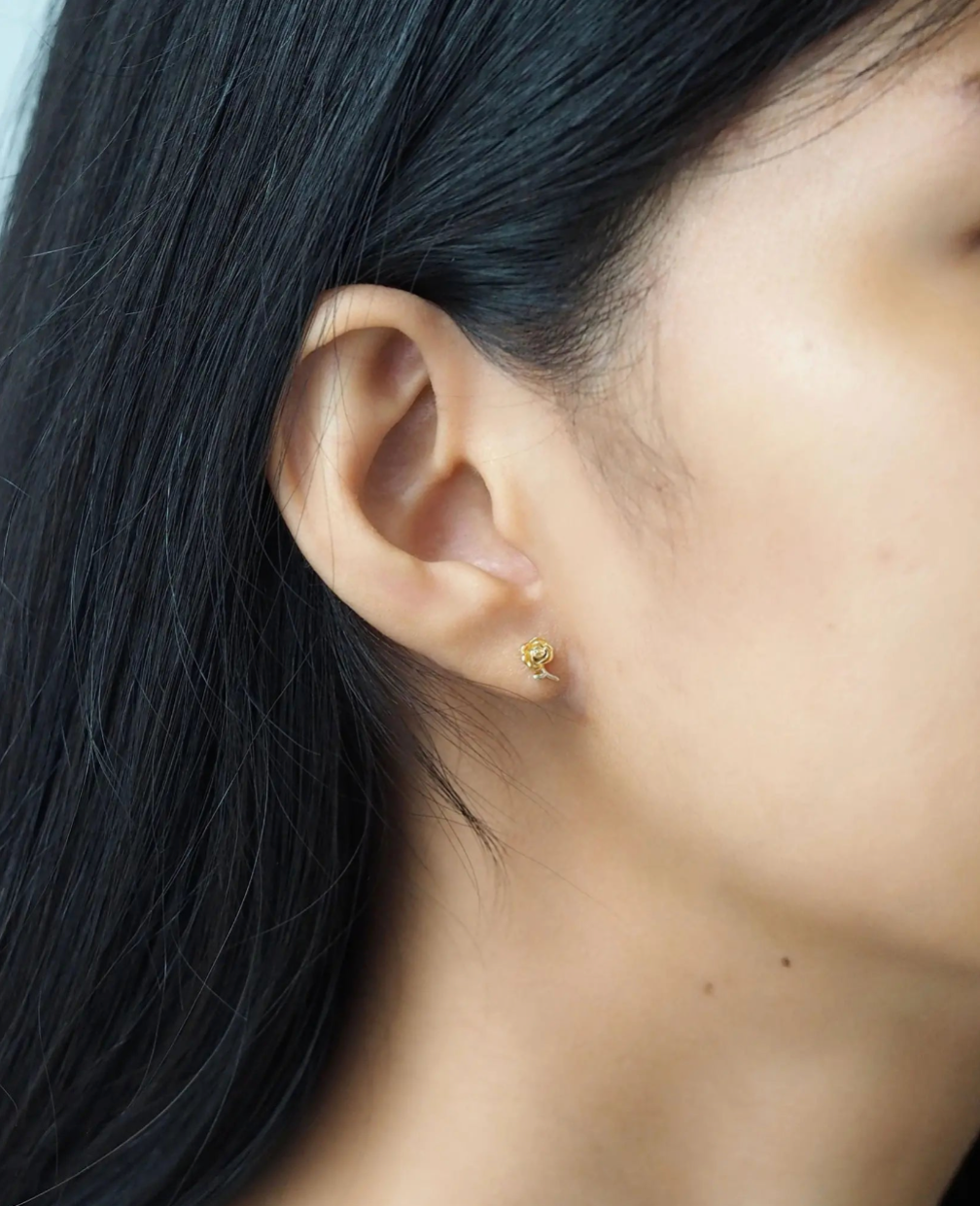 Close-up of an ear with a gold earring against a blurred background