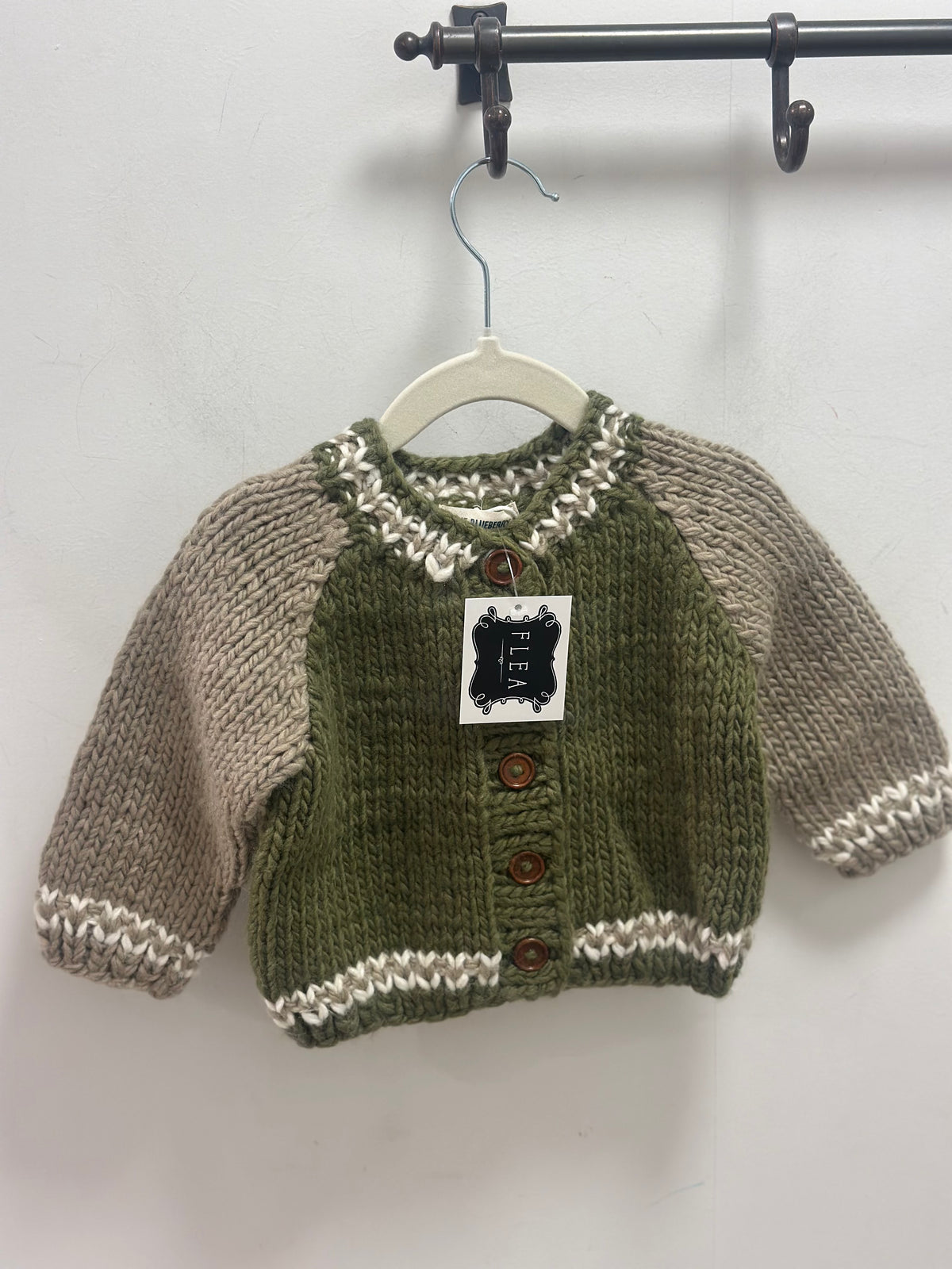 Knitted sweater with buttons on a hanger against a white background