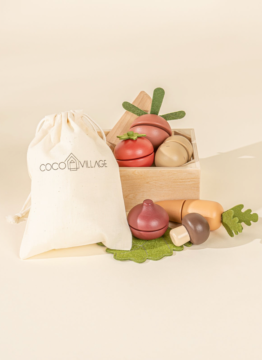 Set of wooden toy fruits and vegetables with a CoCo Village drawstring bag on a beige background