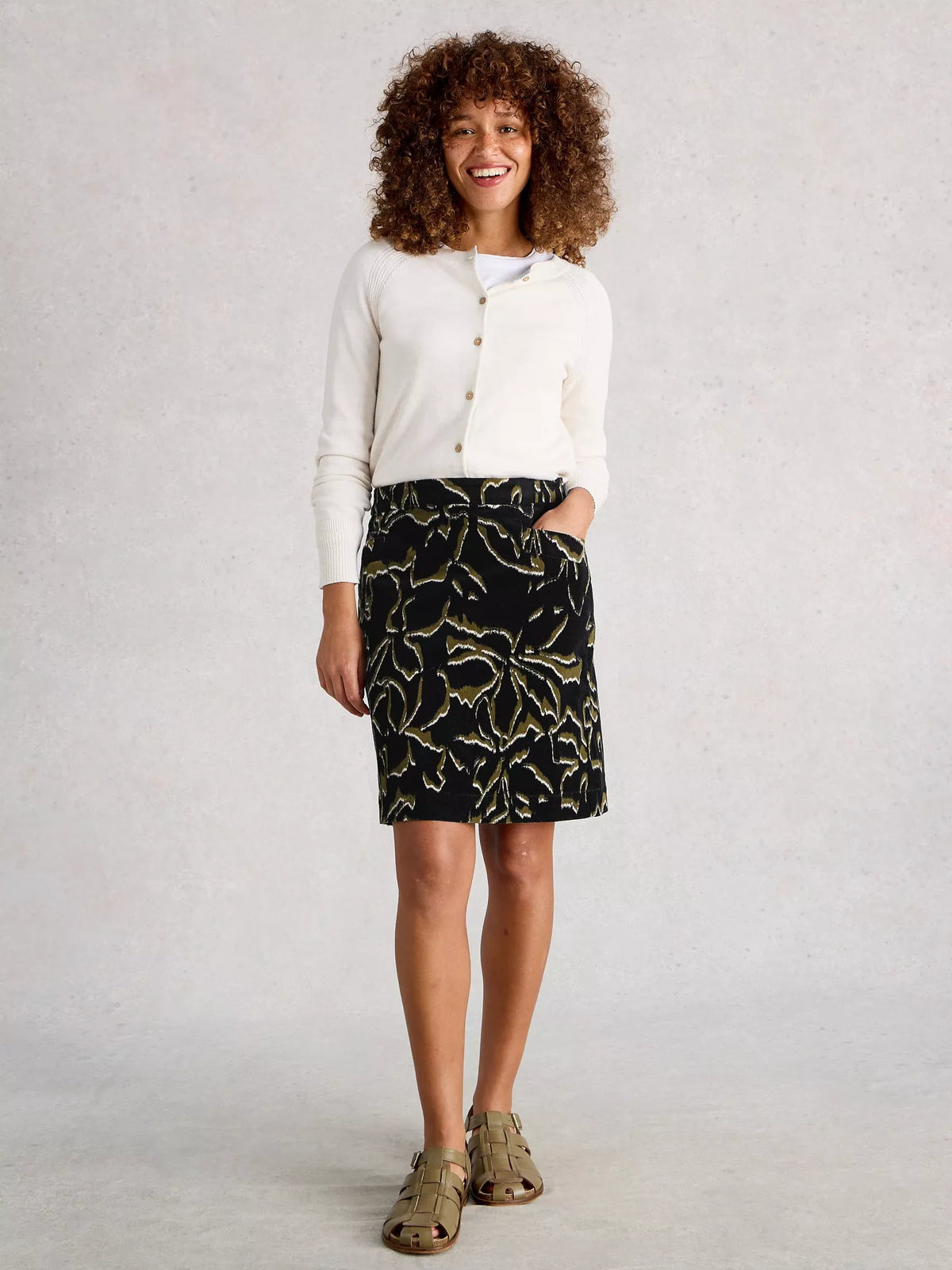 Woman wearing a white blouse and black patterned skirt on a plain background