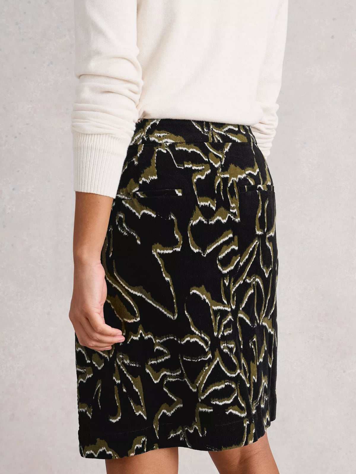 Black patterned skirt worn by a person on a light gray background