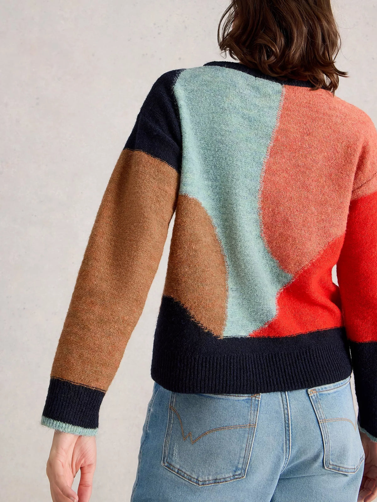 Color-blocked sweater with brown, green, red, and black sections worn by a person.