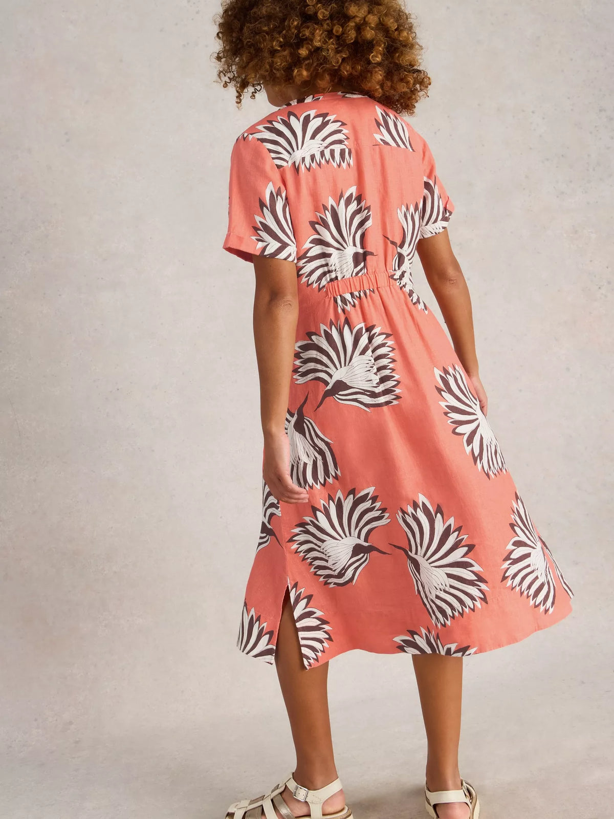 Person wearing a coral dress with black and white pattern on a plain background