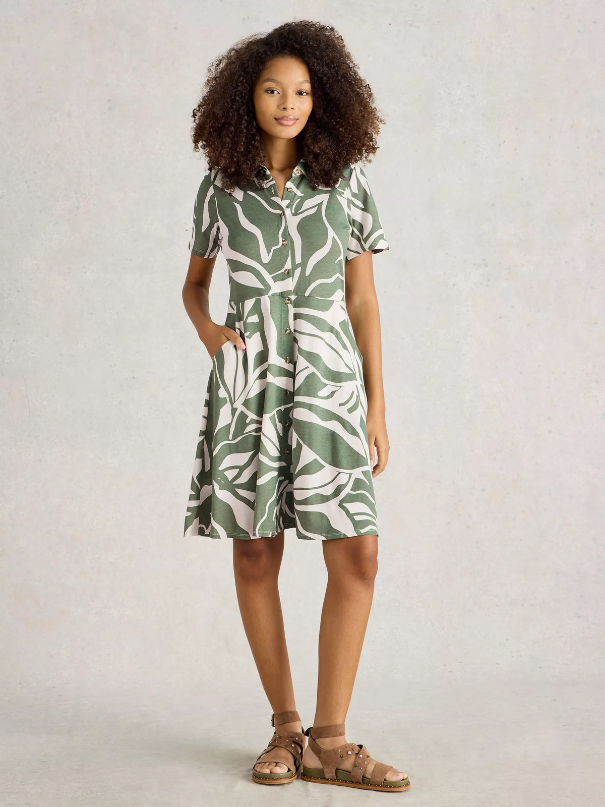 Young girl wearing a green and white patterned dress on a plain background