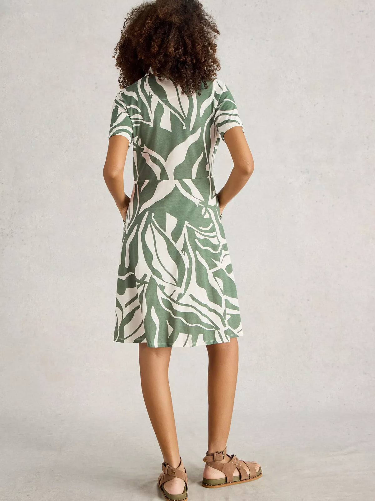 Woman wearing a green and white patterned dress on a plain background