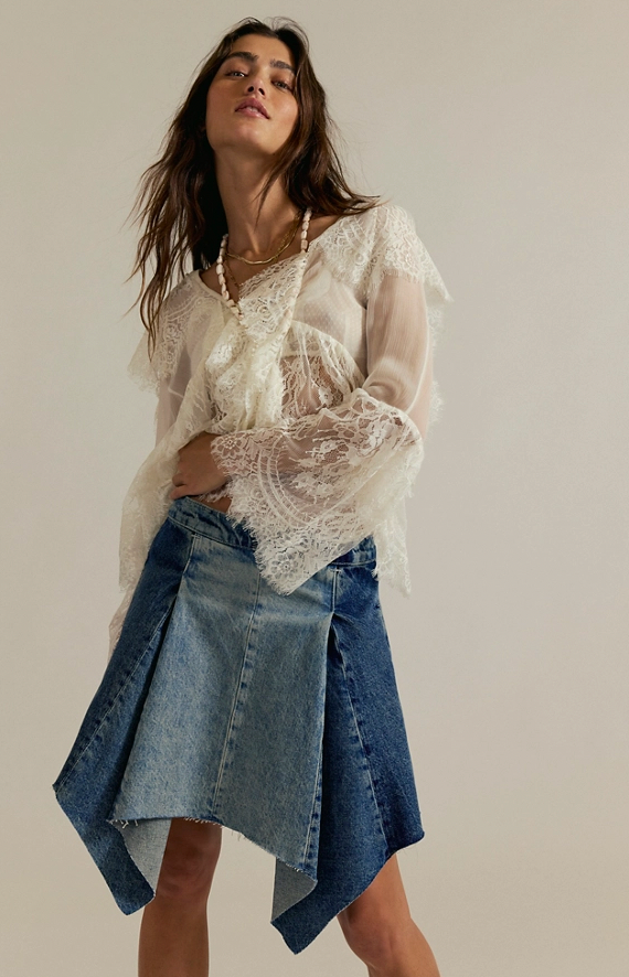 Woman wearing a lace top and denim skirt against a plain background