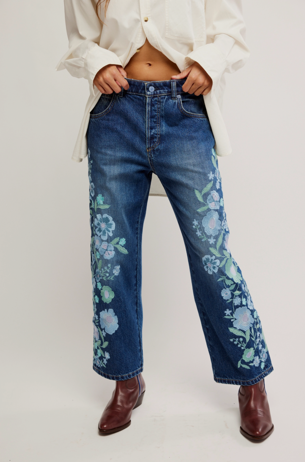 Person wearing blue jeans with floral patterns on a white background