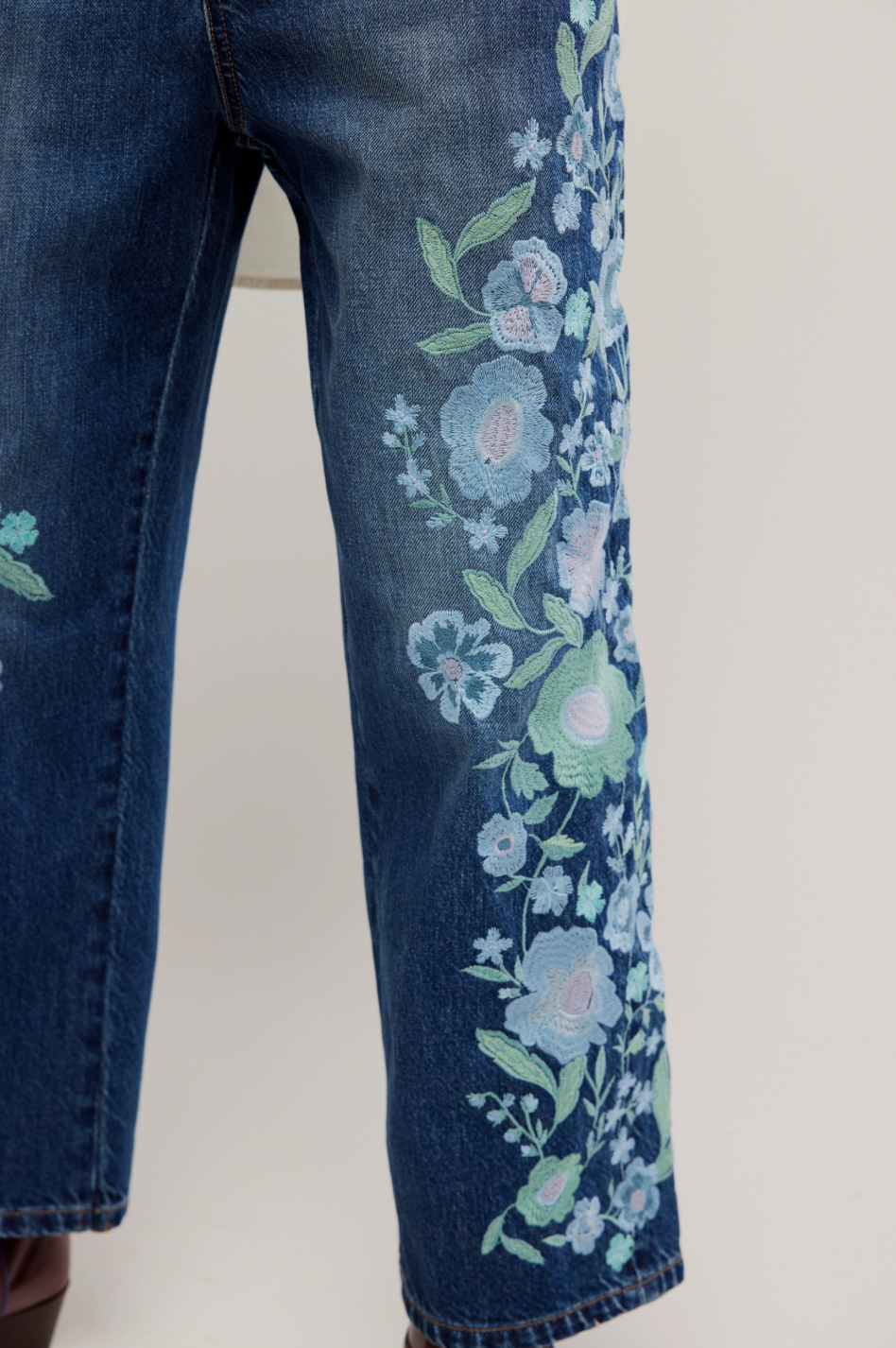 Blue jeans with floral embroidery on a white background