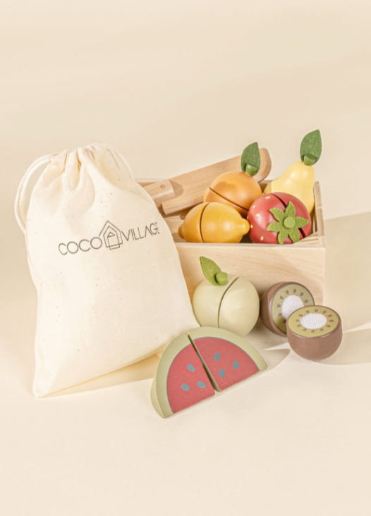 Wooden toy fruits in a box with a drawstring bag labeled coco village  on a beige background